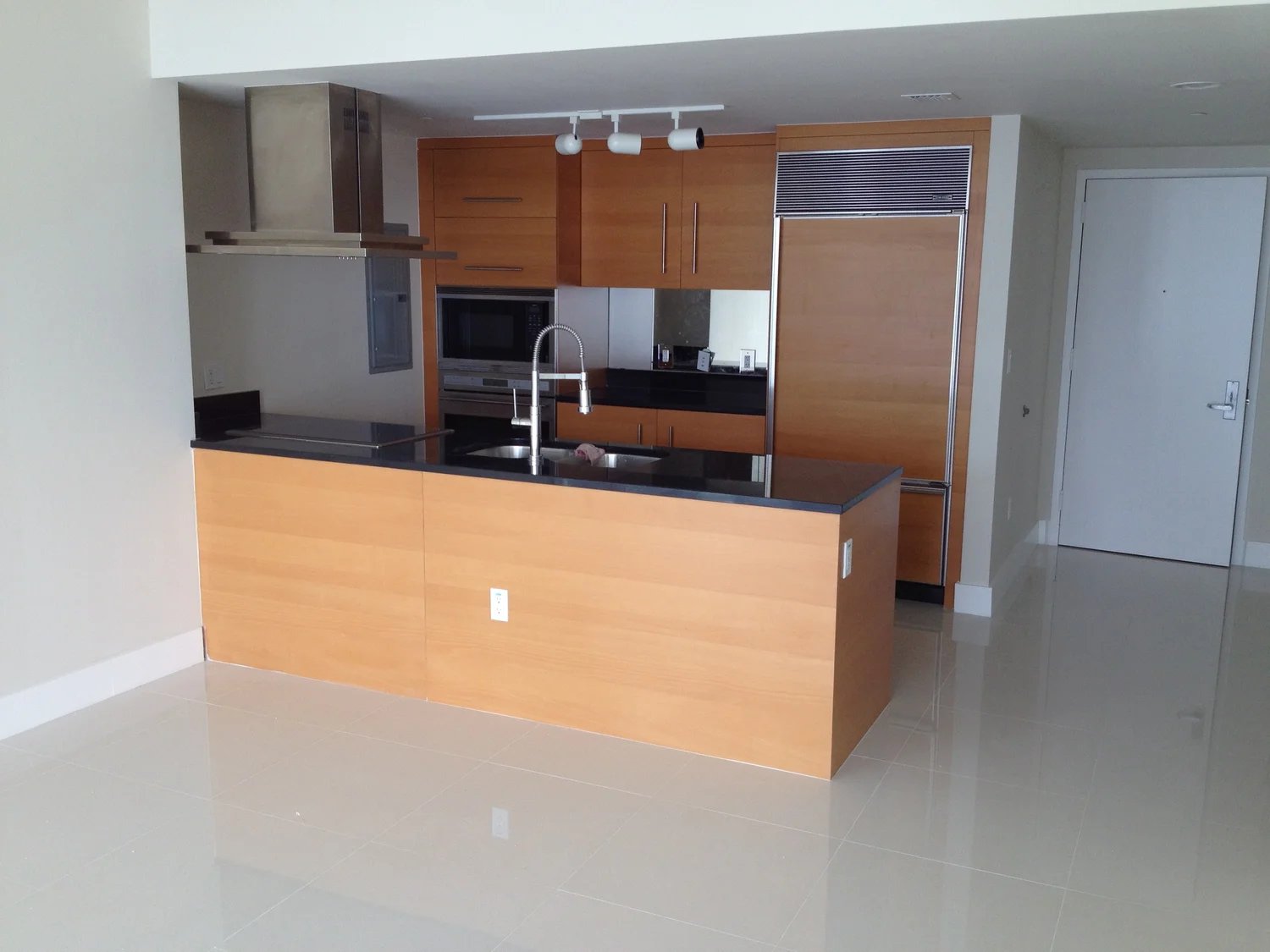 Modern white kitchen with curved island and marble flooring — luxury condo renovation Miami